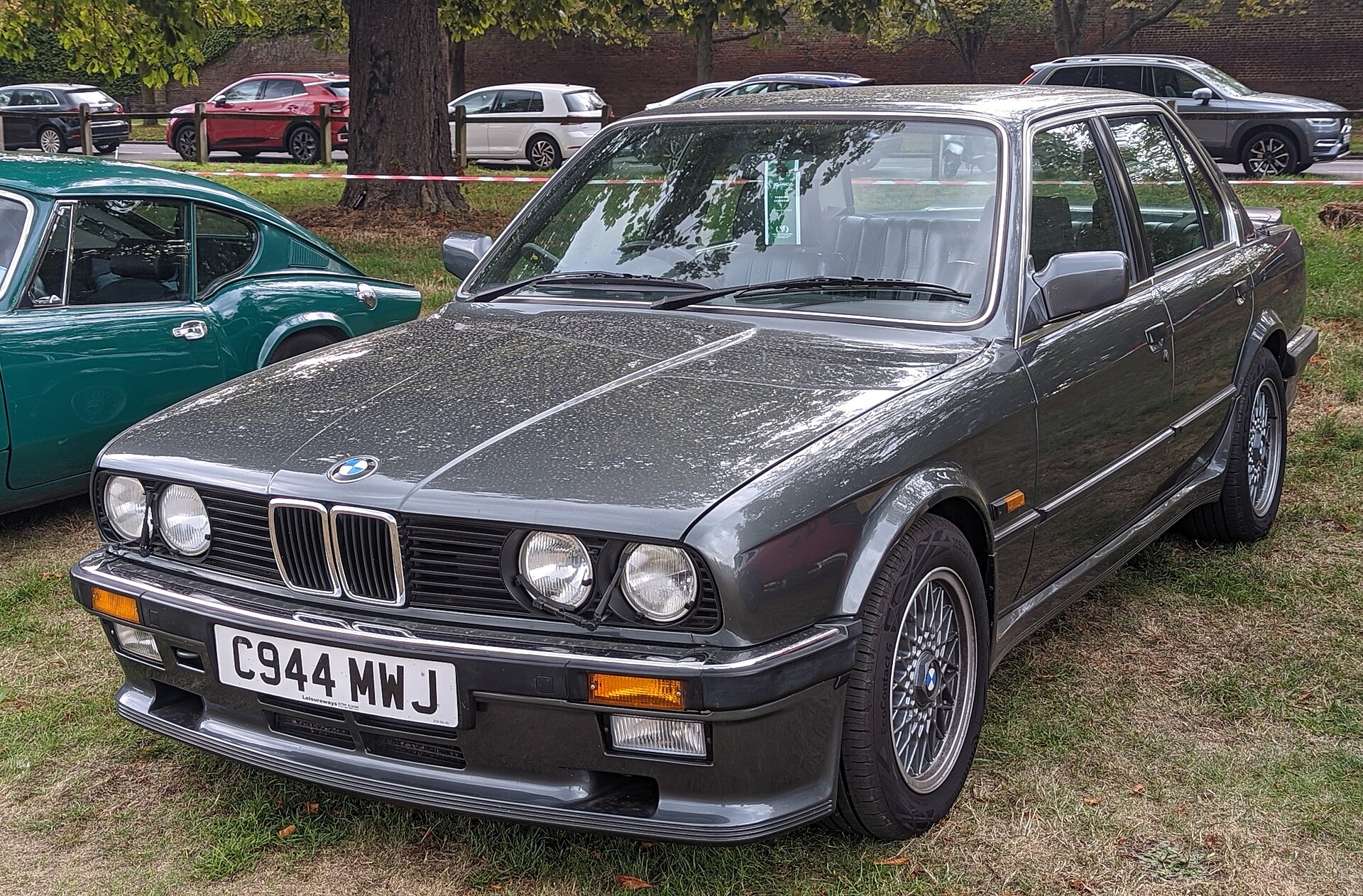 Gray four-door BMW 325i E30 sedan photographed from the front three-quarter view