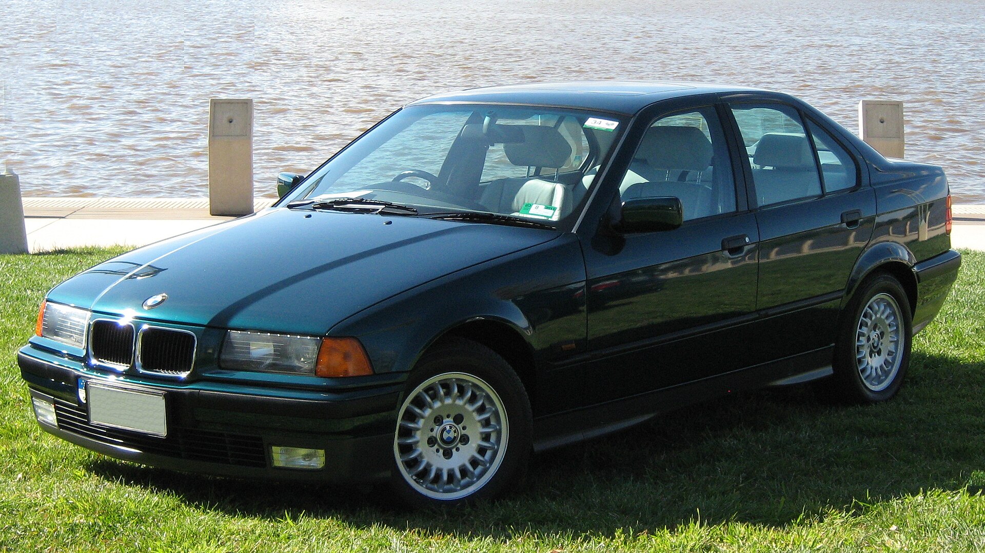 Green BMW 320i E36 sedan photographed from the front three-quarter view
