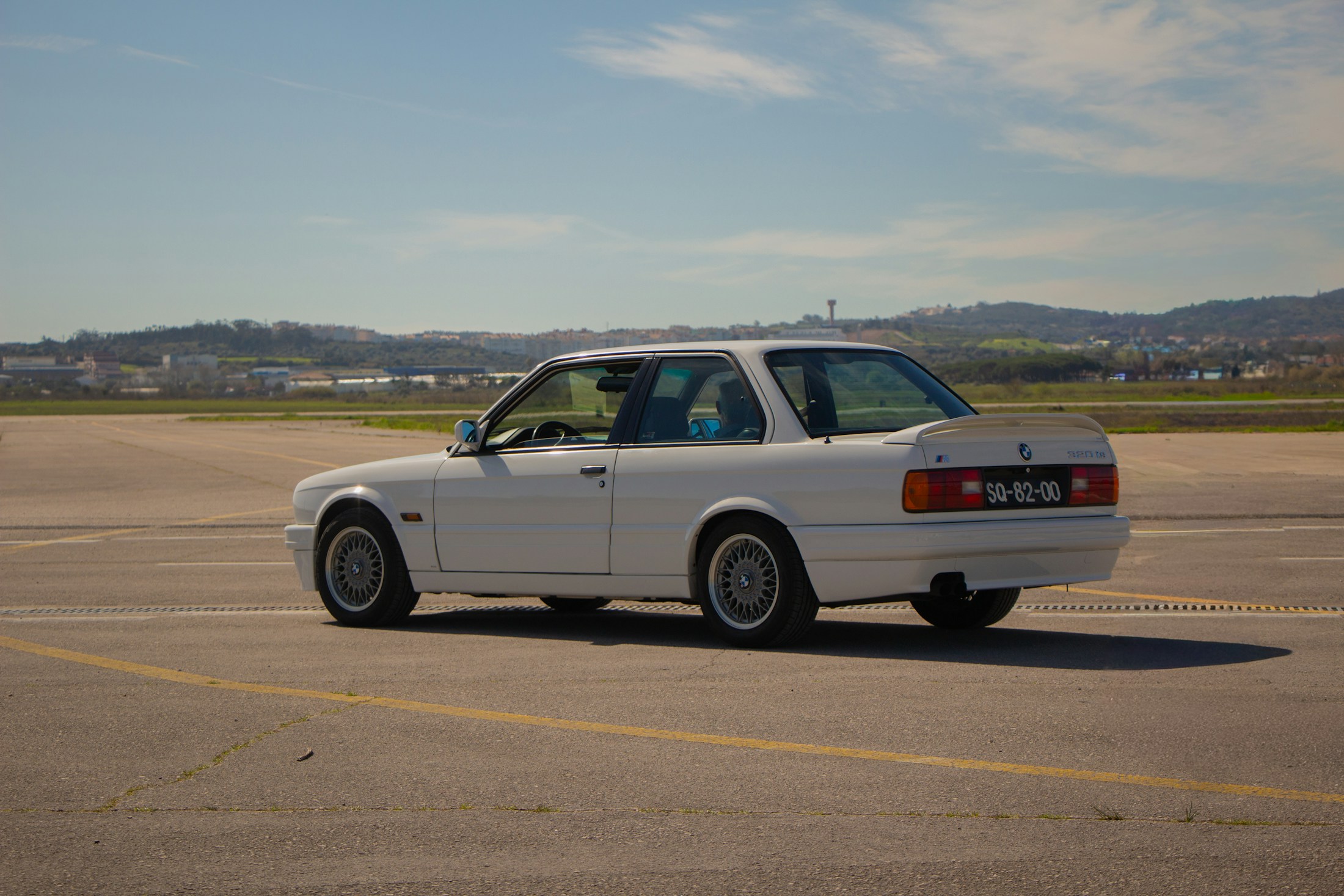 White BMW M3 E30 photographed in full side profile on an airfield