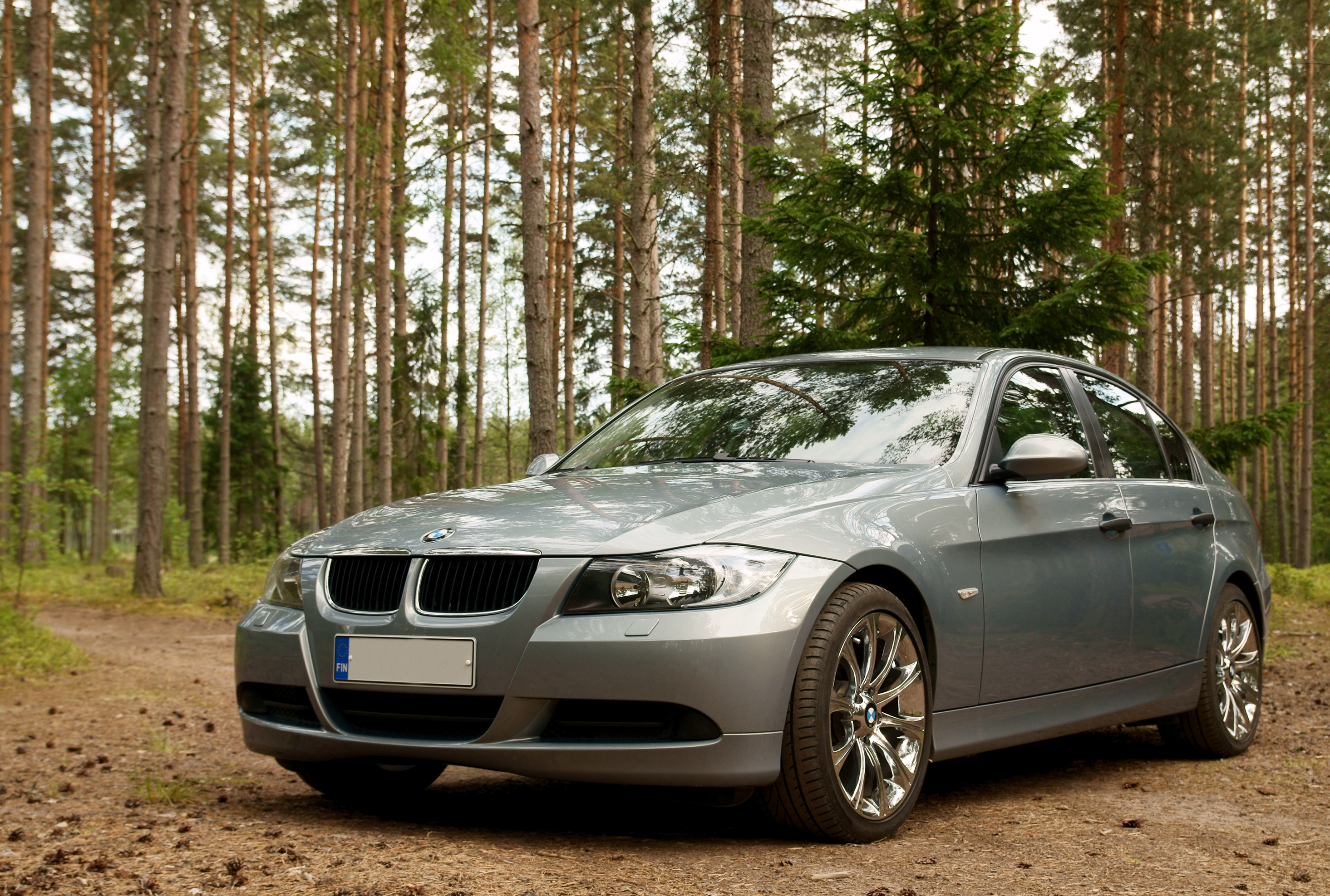 Silver BMW 3 Series E90 sedan photographed beside a Finnish forest